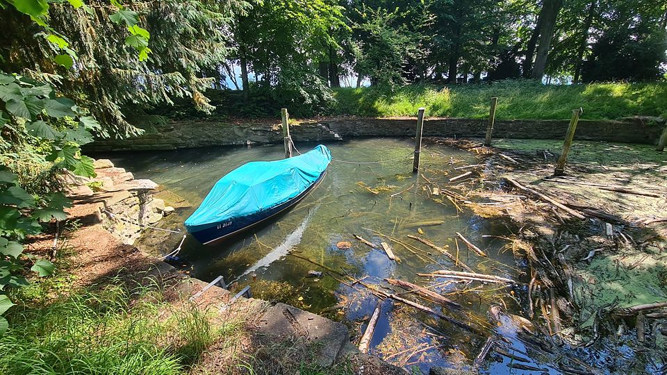 Ein Boot mit türkiser Plane im kleinen Hafen