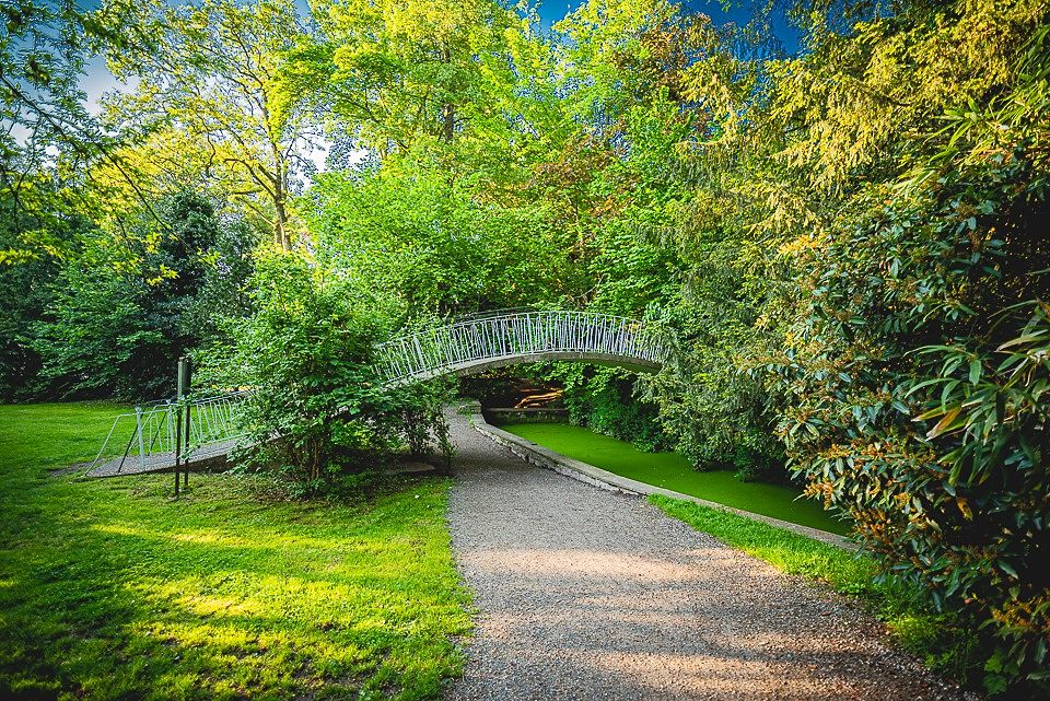 Weiße Brücke über den grünen Weiher im Park